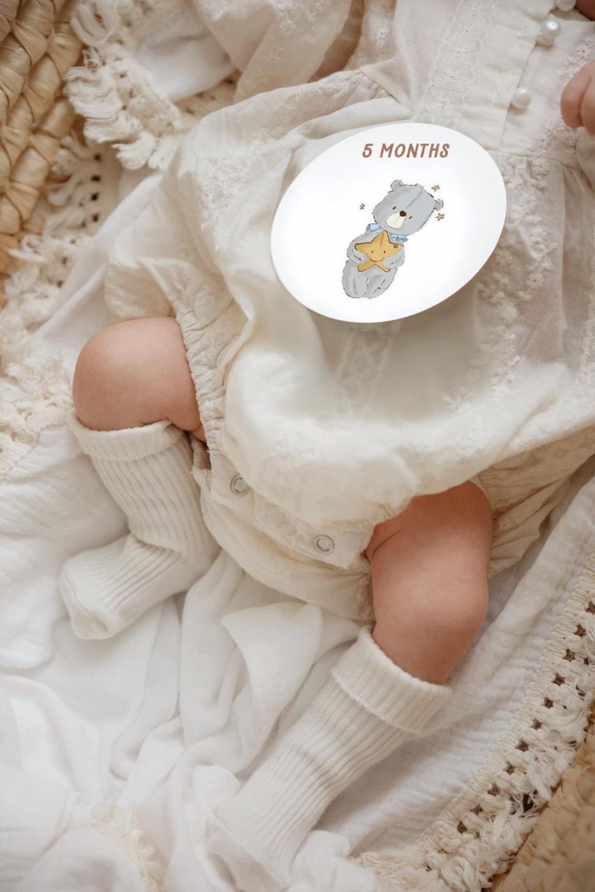 Baby with 5 months milestone card featuring bear illustration